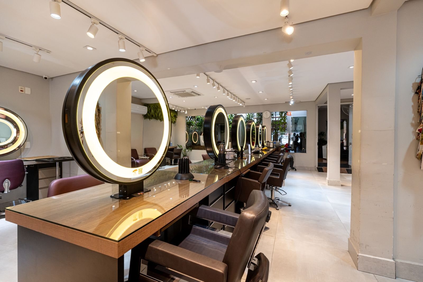 Estações de cabelo com espelhos iluminados e poltronas